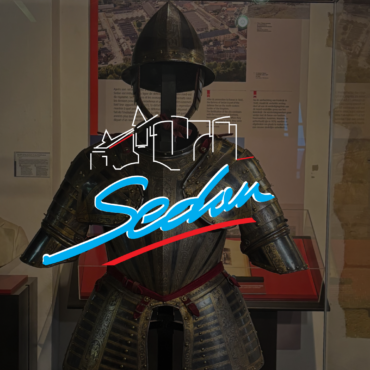 Image d'une armure exposée au château fort de Sedan ainsi que le logo de la ville de Sedan